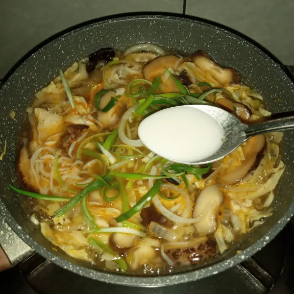 Masukkan irisan daun bawang bagian hijau dan tuang latutan maizena. Masak sampai mendidik dan mengental. Koreksi rasa.
