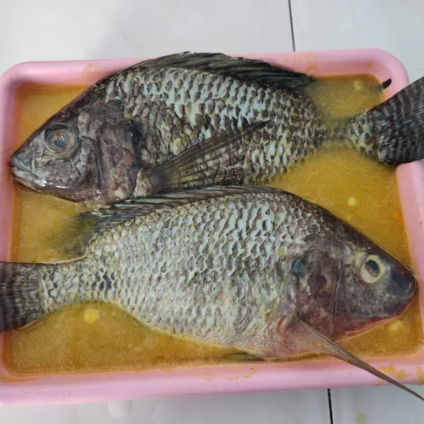 Haluskan bawang putih, kunyit, ketumbar dan garam, tambahkan air. 
Marinasi ikan dengan bumbu halus selama 15 menit.