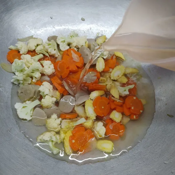 Masukkan bakso, wortel, bunga kol dan jagung.
Tuang air, masak sampai mendidih dan ½ matang.