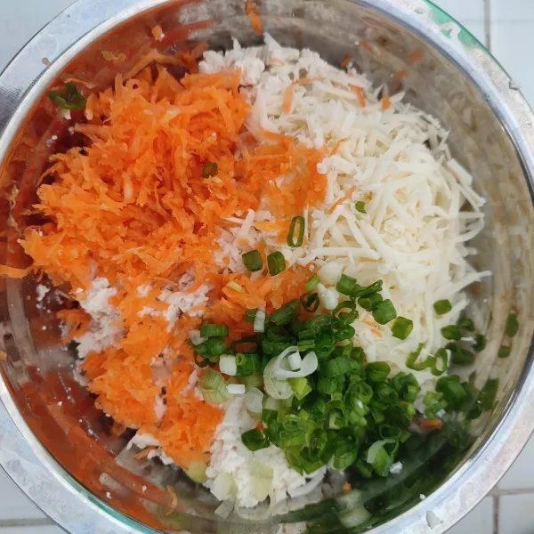 Tambahkan parutan keju, wortel, dan irisan daun bawang, lalu aduk rata.