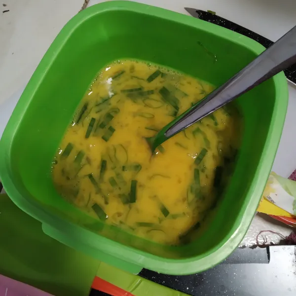 Kocok telur dengan daun bawang dan kaldu bubuk.