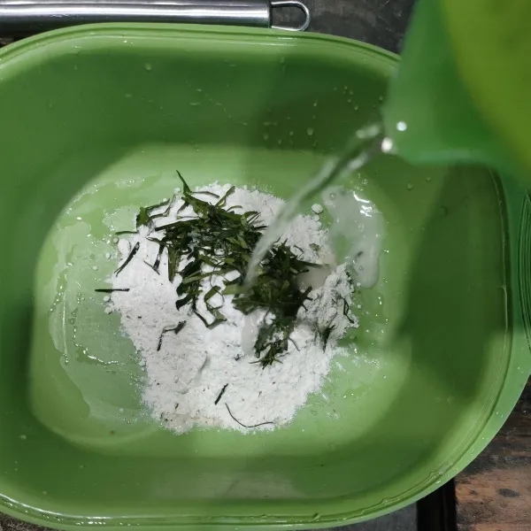 Siapkan wadah, masukkan tepung, irisan daun jeruk, dan air.