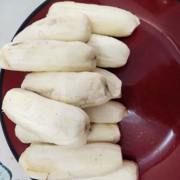 Langkah yang pertama kupas kulit pisang nya kemudian belah menjadi dua bagian.
