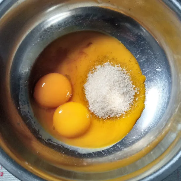 Dalam wadah, kocok menggunakan whisk kuning telur bersama gula dan vanili essence sampai gula larut.
