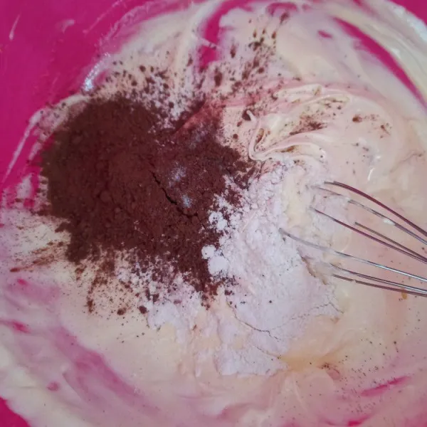 Tambahkan tepung terigu, cokelat bubuk, vanili bubuk, baking powder, dan tahu. Aduk merata menggunakan whisk.