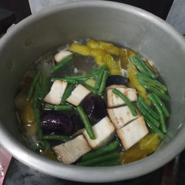 Masukkan kacang panjang, terong dan kulit kedondong. 
Masak hingga setengah matang.