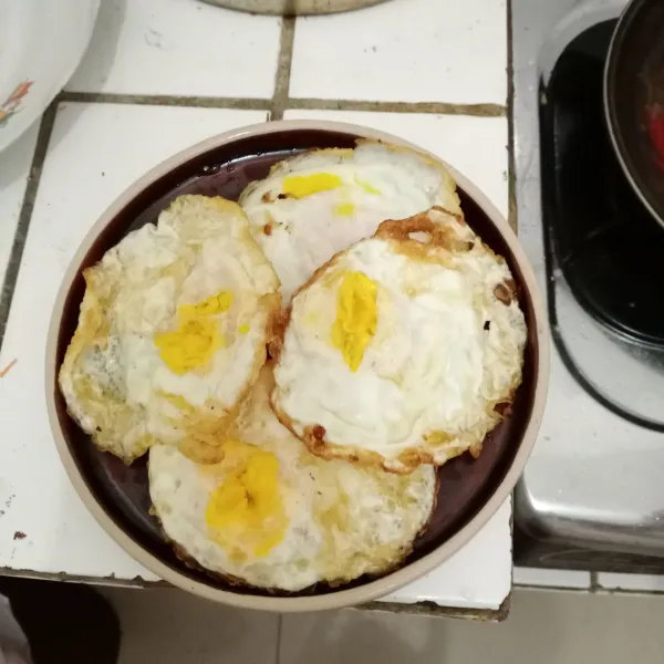 Siram saus tiram di atas telur ceplok yang sudah disusun di atas piring saji.