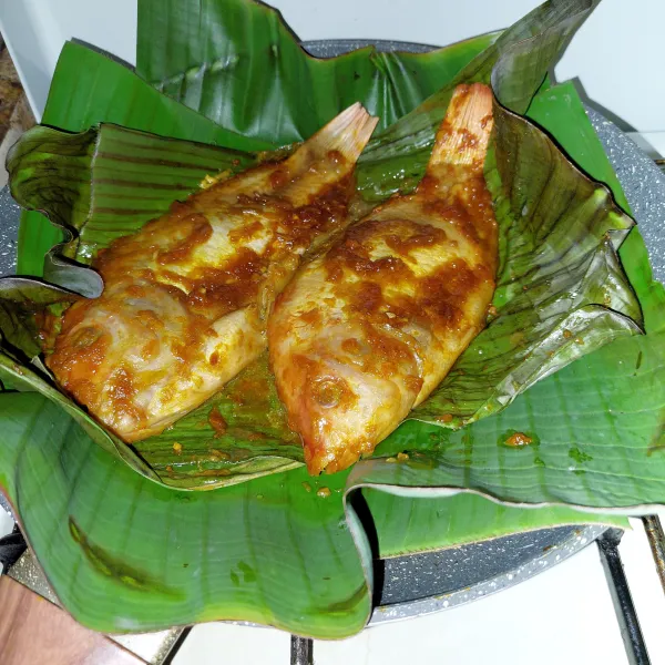 Siapkan teflon dengan daun pisang, tata ikan lalu panggang dengan api kecil selama 15 menit tiap sisi.