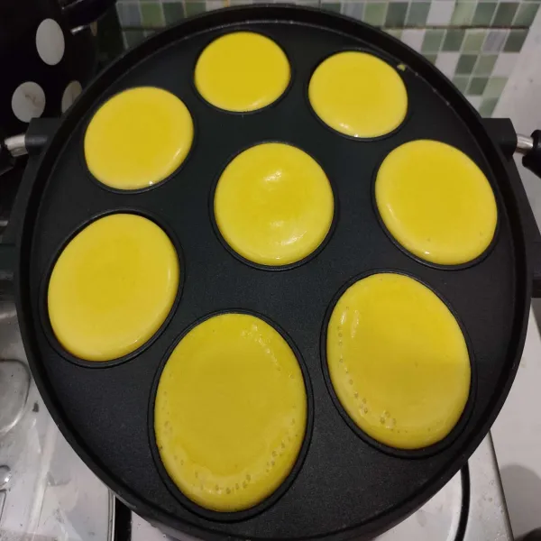 Panaskan cetakan snack maker. 
Alasi cetakan dengan tatakan besi agar tidak cepat gosong. 
Tuang adonan sebanyak ¾ bagian saja. 
Masak dengan api kecil hingga bagian atas berpori.