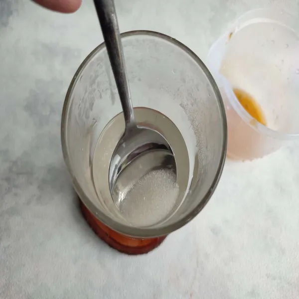 Larutkan gula pasir dengan air panas di dalam gelas saji.