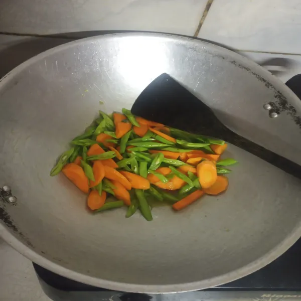 Tumis bumbu dan daun bawang hingga harum, lalu masukkan wortel dan buncis.