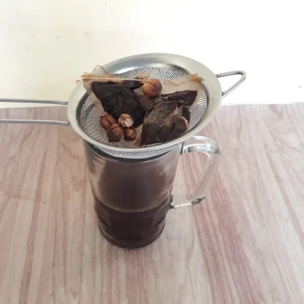 Tuang dan saring air rebusan teh ke dalam gelas.