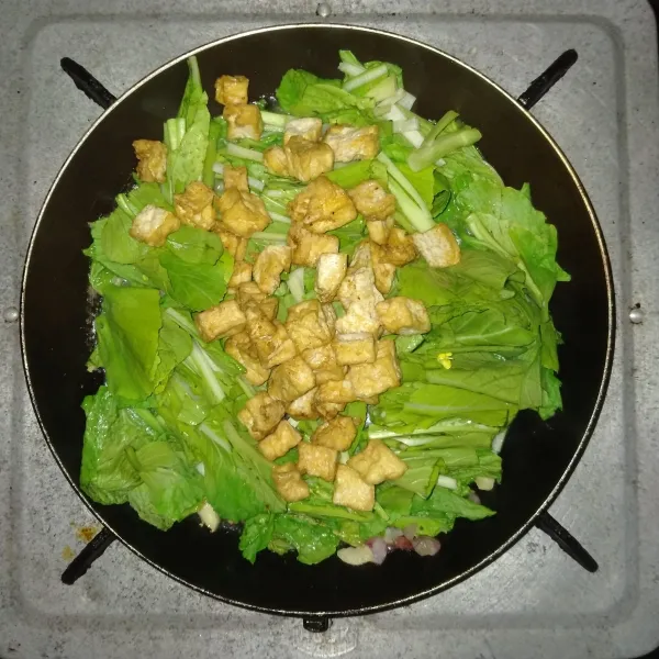Masukkan sawi dan tahu, aduk rata.
