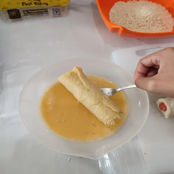 Masukkan roti ke dalam telur kocok hingga semua permukaan basah.