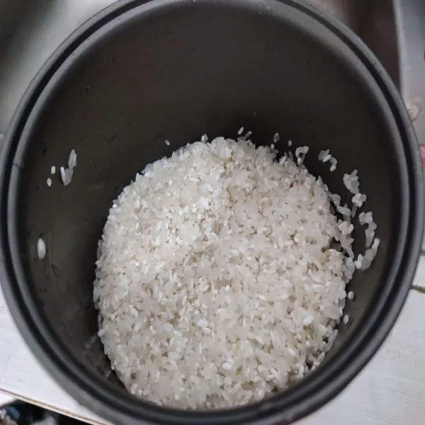 Cuci bersih beras, pindahkan ke dalam panci rice cooker.