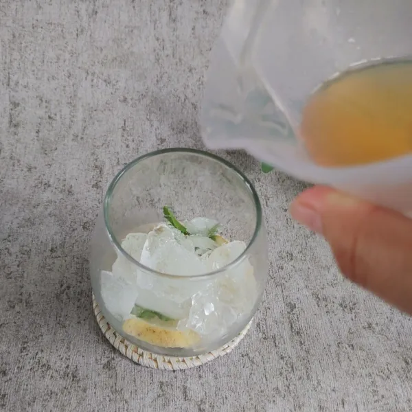 Didalam gelas, masukan irisan lemon, daun mint dan es batu. Tuang simple sirup.