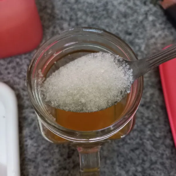 Siapkan gelas, peras dan saring jeruk kemudian tambahkan gula pasir, aduk rata.