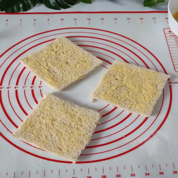 Oleskan secukupnya margarin di kedua sisi roti tawar, lalu sisihkan.