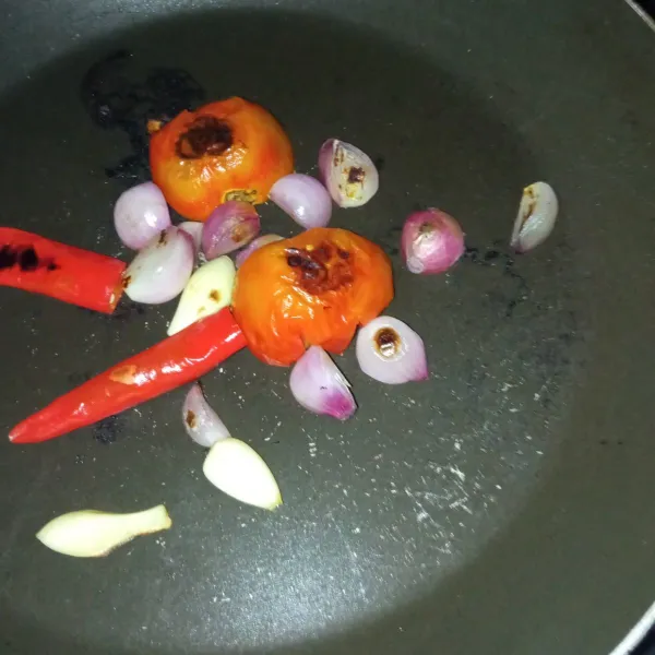 Bakar bawang merah, bawang putih, tomat dan cabe merah di atas teflon.