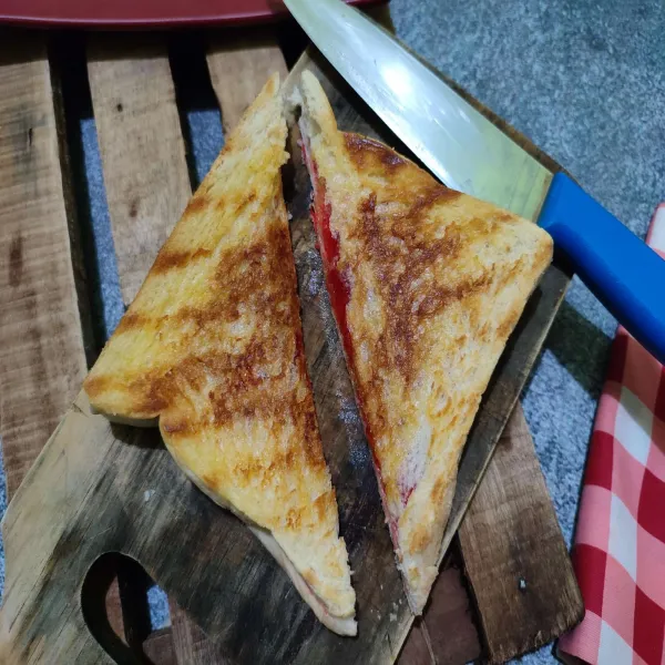 Potong 2 roti bakar seperti bentuk segitiga, kemudian sajikan di atas piring saji.