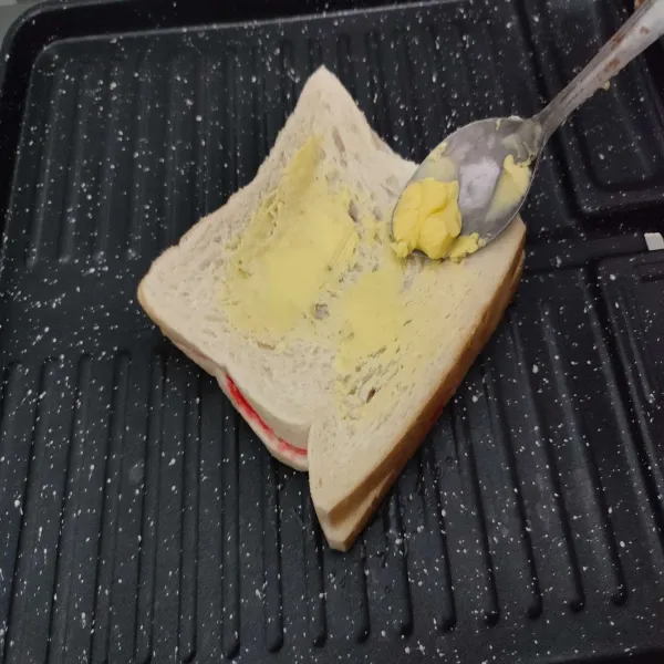 Kemudian oleskan lagi bagian permukaan roti yang belum dipanggang dengan margarin.