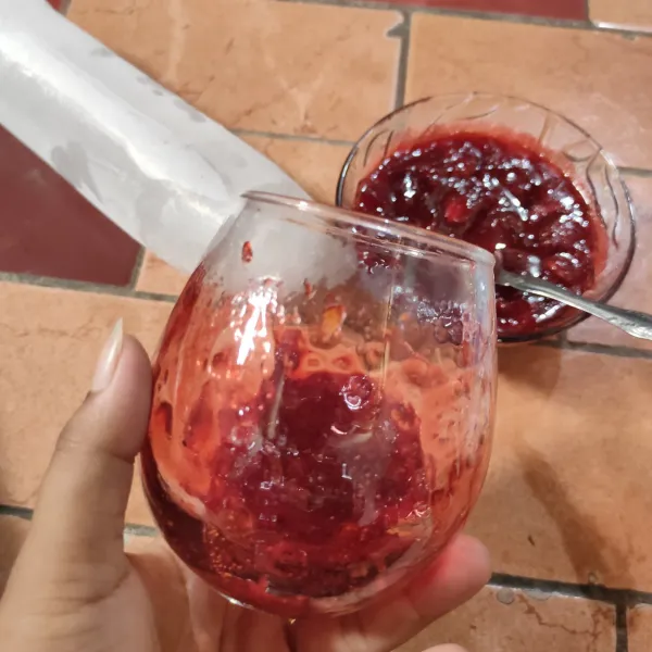 Siapkan gelas saji, masukkan selai strawberry dan ratakan pada pinggiran gelas.