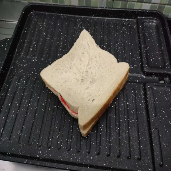 Panggang roti di atas grill pan dengan bagian yang diolesi margarin menghadap ke bawah.
Panggang dengan api kecil.