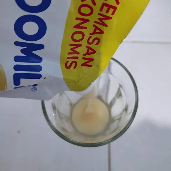 Tuang susu kental manis ke dalam gelas.