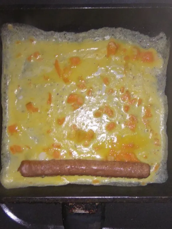 Tuang sedikit adonan telur kedalam wajan lalu letakkan sosis di atas telur.