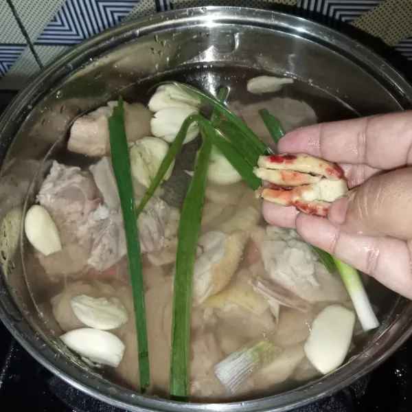 Rebus ayam, air, bawang putih, jahe dan daun bawang dengan api sedang.
