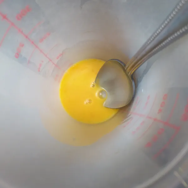 Masukkan kuning telur ke dalam gelas, lalu kocok lepas.