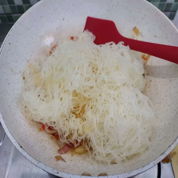 Masukkan bihun yang sudah direndam air panas, kemudian aduk cepat.