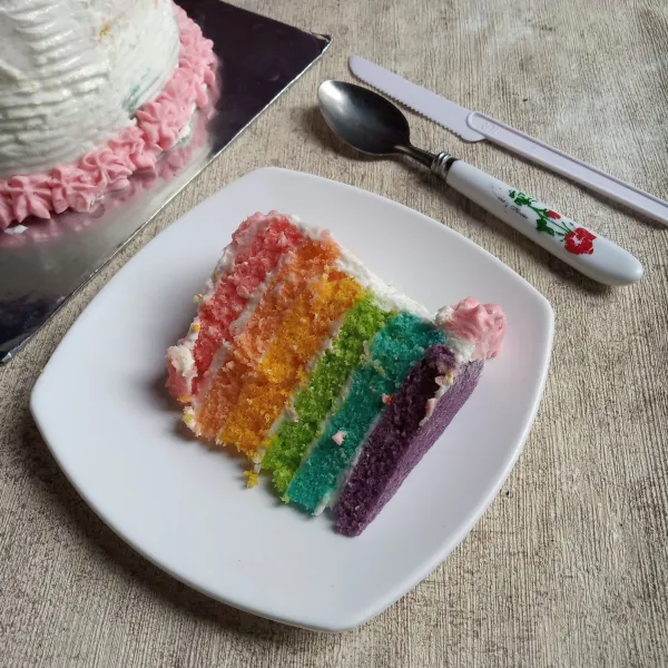 Potong rainbow cake kukus menggunakan pisau kue, sajikan.