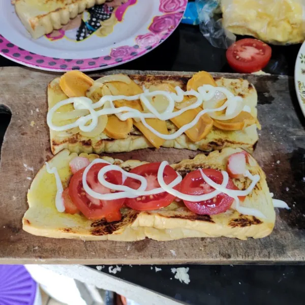 Isi bagian pertama roti dengan crab stick, bawang bombay, tomat lalu beri mayonnaise. 
Isi bagian kedua roti dengan sosis, bawang bombay dan mayonnaise.