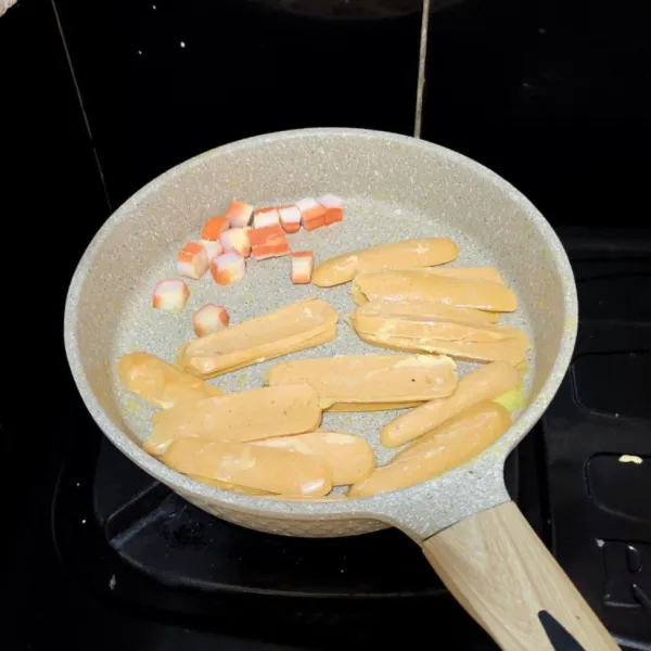 Oleskan margarin kemudian masukkan sosis yang telah diiris tipis dan crab stick yang telah dipotong-potong kemudian masak hingga kering.