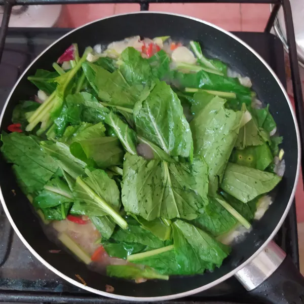 Masukkan sawi, aduk rata sampai layu.