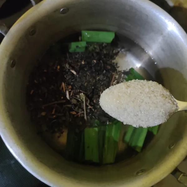 Masukkan daun teh kering dan gula pasir, aduk rata.