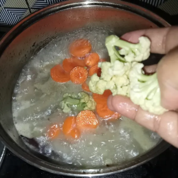 Setelah setengah matang, masukkan kembang kol dan wortel, masak hingga semuanya matang.