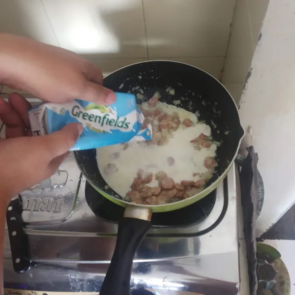 Masukkan tepung terigu, aduk rata, lalu tuang susu cair.