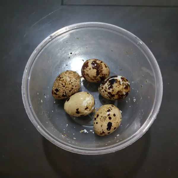 Rebus telur puyuh hingga matang, ambil beberapa butir telur, masukkan ke dalam wadah bertutup, guncang-guncang hingga kulit telur retak.