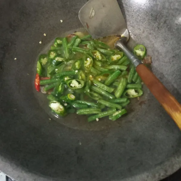 Tuang air, biarkan mendidih lalu masukkan kacang panjang dan cabai hijau. Masak hingga setengah matang.