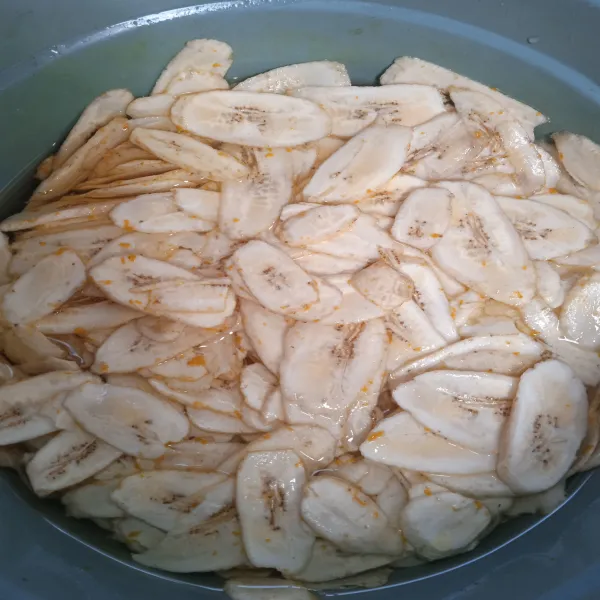 Potong tipis-tipis pisang kemudian rendam dengan pewarna kunyit sedikit saja kurang lebih selama 1 jam.
