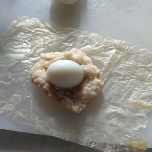 Ambil 1 lembar kulit tahu, letakkan sedikit adonan ekado di atasnya. 
Lalu beri telur puyuh rebus.