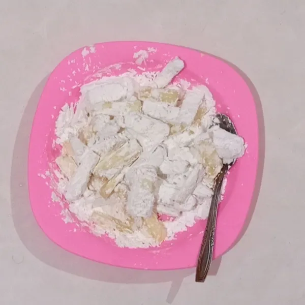 Beri tepung tapioka, baluri hingga singkong tertutup merata.