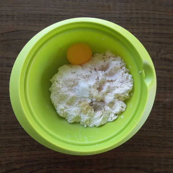 Campurkan tahu, bawang putih, kuning telur, garam, kaldu bubuk, merica dan baking powder ke dalam wadah. 
Aduk-aduk sampai tercampur rata.