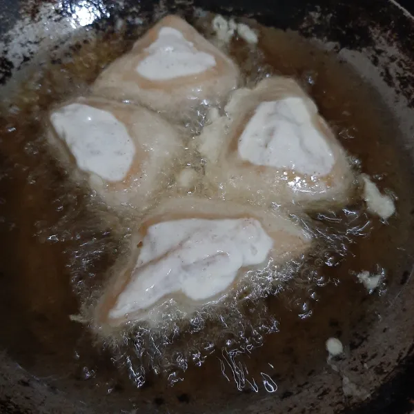 Panaskan minyak goreng dalam wajan. Masukkan tahu isi ke dalam adonan tepung, lalu goreng sampai kedua sisi berwarna cokelat keemasan.