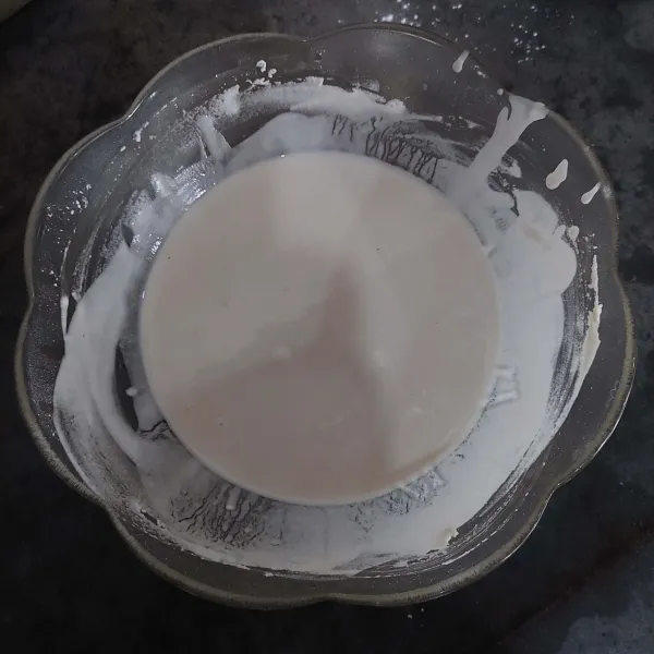 Tambahkan air sedikit demi sedikit, aduk hingga semua bahan tercampur rata dan adonan encer cenderung kental.