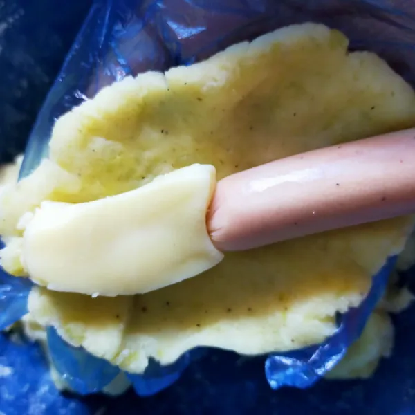 Bagi adonan kentang menjadi 6 bagian sama rata, ambil satu bagian, kemudian pipihkan. Letakkan tusukkan sosis  di adonan kentang, tutup rapi dengan adonan kentang. Lakukan sampai habis.