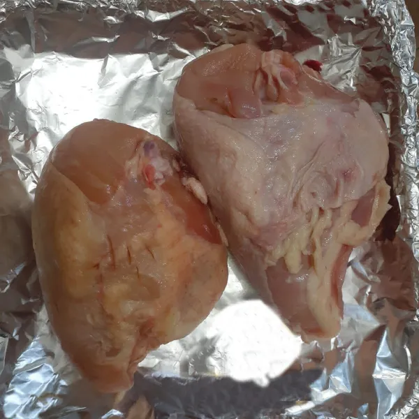 Siapkan wadah lalu alasi dengan alumunium foil. Letakkan ayam dan tusuk-tusuk permukaan ayam dengan garpu.