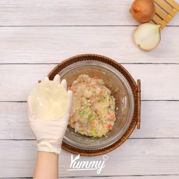 Ambil kulit pangsit bulat dan beri campuran kimchi di dalamnya, bungkus sesuai gambar.